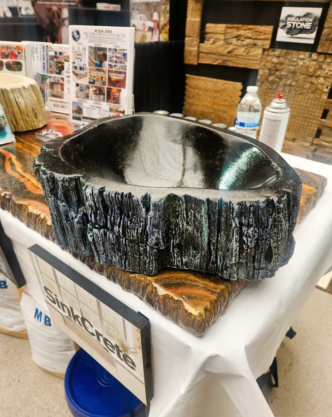 Side view of the black SinkCrete vessel sink on its show stand.